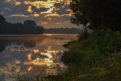 Sun rises through clouds over the Fox River