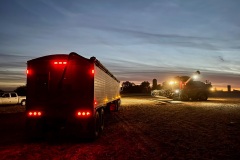 A combine harvesting soybeans prepares to offload into a waiting truck